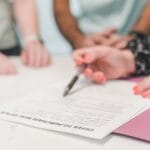 Zbliżenie na osoby przeglądające i podpisujące ofertę zakupu mieszkania