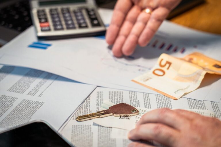 Dłonie nad dokumentami, banknotem 50 euro i kluczem do mieszkania